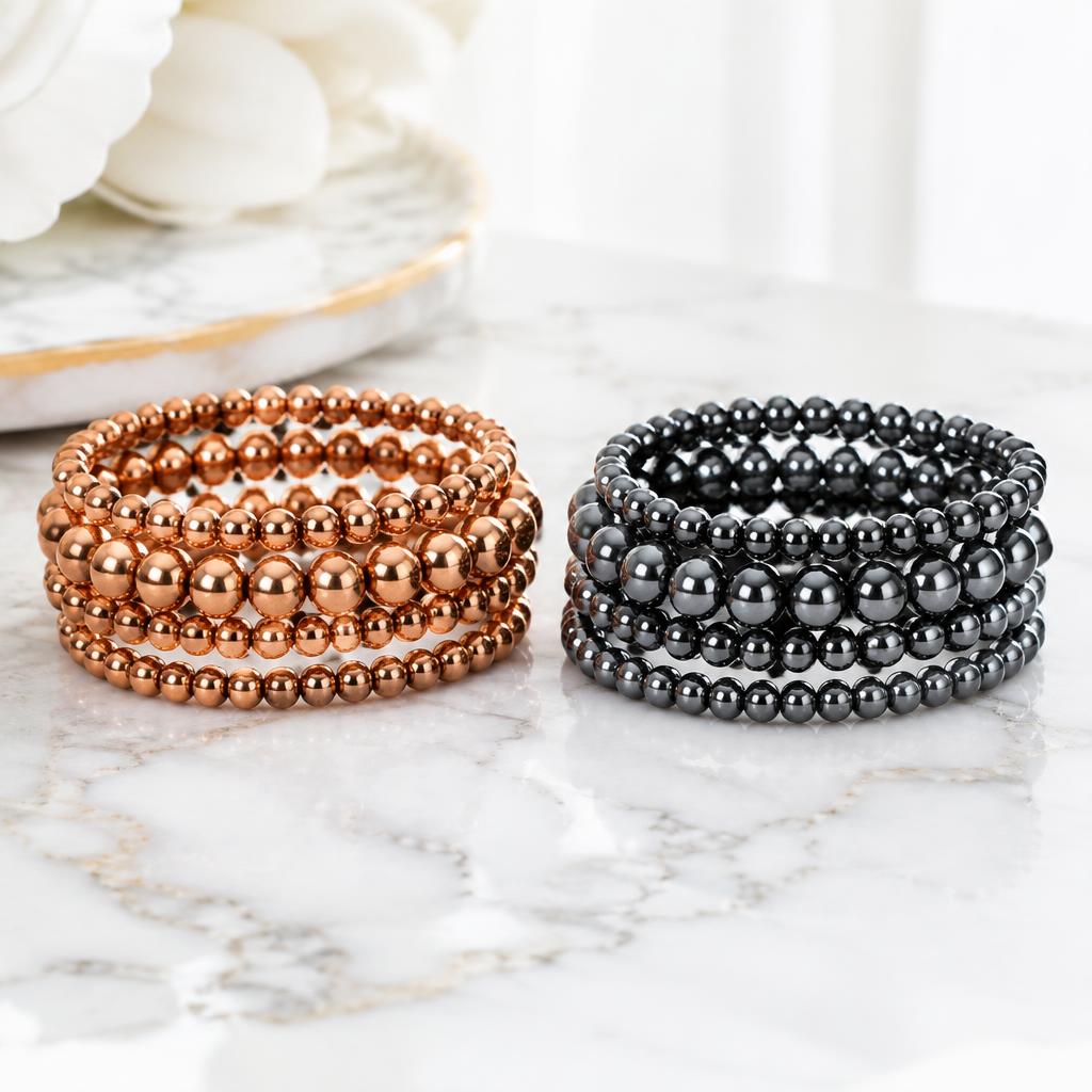 Copper and hematite bracelets stacked together on a pale surface
